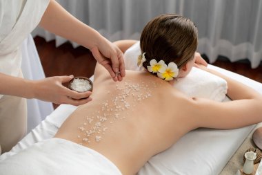 Lüks spa salonlarında sıcak mum ışığında cilt bakımı yaptıran kadın müşteri. Sağlık Spa vücut fırçasında tuz temizleme güzellik tedavisi. Sessiz.