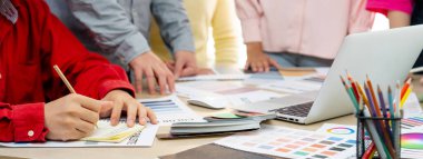 Profesyonel iç mimarın kırpılmış bir görüntüsü, renk örnekleri ve renk paleti belgeleriyle karşılaştırarak iş arkadaşlarıyla renk materyalini tartışıyor. Yaratıcı tasarım konsepti. Değiştirilmiş.