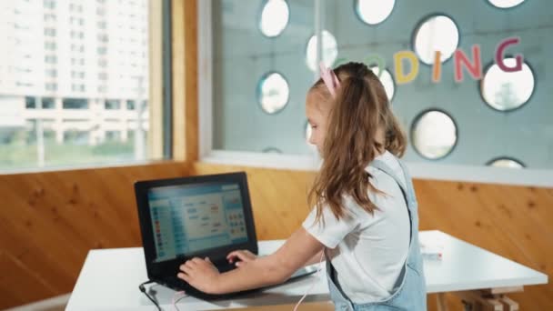 Mosolygó Lány Néz Miközben Integet Kamera Előtt Laptoppal Asztalon Gyermek — Stock videók