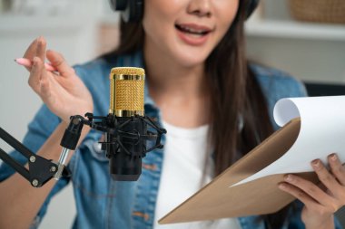 Sosyal medyada kulaklıkla canlı yayın yapan Asyalı sunucu modern stüdyoda yaşam koçluğu veya pazarlama dinleyicilerini selamlıyor. Taktik.