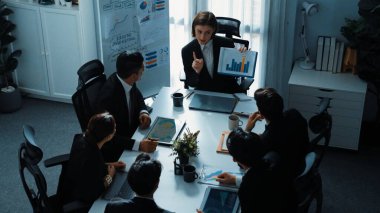 Akıllı iş kadınlarının en üst görüşü çeşitli iş adamlarına satış tablosunun arttığını gösterirken, bir grup farklı iş adamı da masada belgelerle hisse yatırım verilerini dinleyip analiz ediyor. Müdürlük.