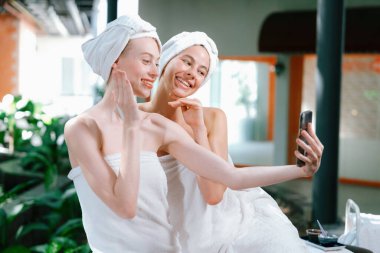 Beyaz havluyla güzel ciltli bir çift güzel kadın açık havada barışçıl doğal çevreyle çevrili bir şekilde fotoğraf çekiyorlar. Güzellik ve sağlıklı spa konsepti. Huzur.