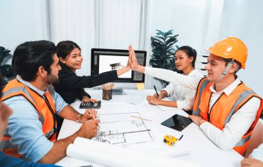 Çeşitli inşaat mühendisi ve müvekkil grupları, mimari proje üzerinde başarılı bir anlaşma yaptıktan, inşaat planını gözden geçirdikten ve toplantı masasında plan oluşturduktan sonra kutlama ve beşlik çakışma yaptılar.