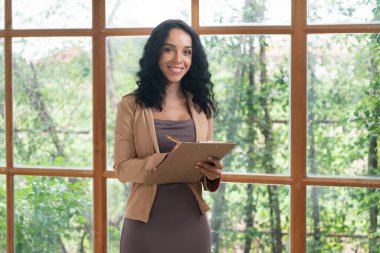 Klinikteki psikolog kadın. Profesyonel portresi. Dostane gülümsemesiyle hastayı psikoloğa davet ediyor. Deneyimli ve kendinden emin psikolog çok önemli bir uzmandır.