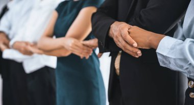 Mutlu ve gülümseyen çok ırklı ofis çalışanı, sinerjiyi ve ticari başarı için işbirliğini destekleyen bir kuyrukta el ele tutuşuyor. Modern işyerinde çeşitli profesyonel ofis çalışanları arasında bağ var. Uyum