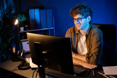 Neon Light Modern Ofis 'te yaratıcı bir başlangıç projesi için bilgisayara odaklanan gülümseyen genç iş adamı. Düşünüyorum da, pazarlama ağı yaratıcıdan pazar kanalı tasarım konseptine çevrimiçi planlama. Toplayıcı.