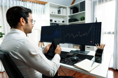 Akıllı tüccar işadamı, modern merkez ofisindeki araştırma pazarında en yüksek kârlı finansal teknolojiye yatırım yaparak bilgisayar üzerinde iki dinamik borsa yatırım ekranını analiz ediyor. Tahmin et..