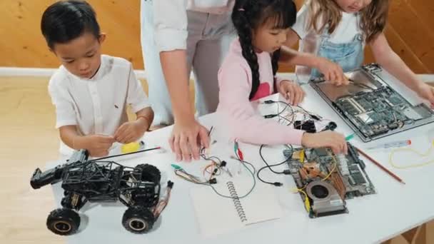 高视角的高加索教师教授和解释学生的数字电动工具 女孩学习电子设备 并用芯片和电线把主板固定在桌子上 Erudition — 图库视频影像