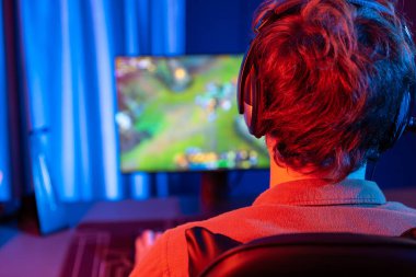 Savaş arenasında çoklu oyunlar takımıyla Moba 'da savaşan genç oyun flamasının sunucu kanalı, neon dijital ışık modern odasındaki arka görüntü ile bilgisayar monitöründe kulaklık takıyor. Toplayıcı.