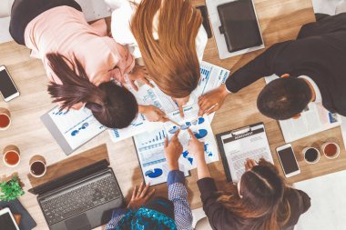 Modern ofisteki iş adamları ve iş kadınlarıyla grup toplantısındaki iş adamlarının en üst düzey görüşü, masada dizüstü bilgisayar, kahve ve belge ile. Kurumsal şirketler uds