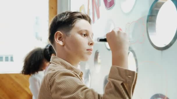 在艺术课上 高加索创意学生的服装在玻璃板上画出美丽的图画 聪明的男孩使用标记绘图 而多文化的朋友一起起草 创新教育 Erudition — 图库视频影像