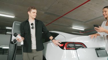 Elektrikli araba sürücüsü, arabadaki uygulama ekranında şarj durumu, menzil ve şarj limitini kontrol ediyor. Akıllı teknoloji aygıtı, EV arabasının araba aküsündeki elektrik depolama verilerini şarj ettiğini gösteriyor..