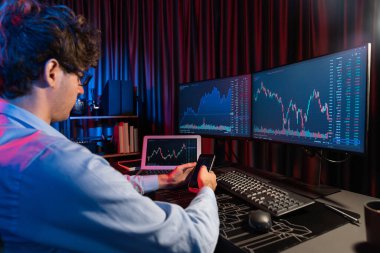 Akıllı telefonlara odaklanan genç tüccar ile piyasa stoku grafiğindeki dizüstü bilgisayarla Neon Light Modern Ofis 'teki gerçek zamanlı ekranları karşılaştırıyor. Dinamik döviz kurunu analiz etme kavramı. Toplayıcı.