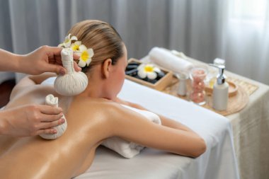 Sıcak bitkisel top spa masaj vücut tedavisi, masör kadın vücuduna nazikçe şifalı bitki torbası bastırıyor. Aromaterapi dinlenme sükuneti ve sükuneti kaplıca salonundaki atmosferi aydınlatıyor. Sessiz.