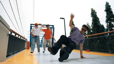 Panorama 'da hipster şık kıyafetler giyer ve dondurucu poz verir. Bir grup profesyonel dansçı break dans yaparken seçkin adam break dans yapıyor. Açık hava sporu 2024. Yumuşak bir şekilde.