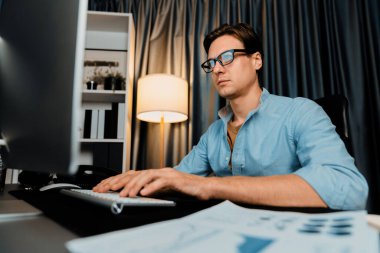 Akıllı iş adamı iş paragrafı dinamik pazarlama analizi planını analiz ediyor. Kağıt kağıtları ve bilgisayar monitörü raporlarını gece evdeki belge verileriyle karşılaştırmak için hazırlıyor. Bireysel.