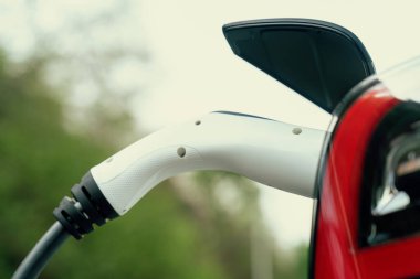 Kapalı EV şarj kolu fişe takıldı veya elektrikli arabaya bağlandı, EV araba aküsünü temiz çevre için sıfır CO2 emisyonu ile alternatif ve sürdürülebilir enerjiyle şarj etti. Kalıcı