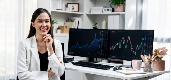 年轻的亚洲女商人面带微笑 面带微笑 身穿白色西服坐在椅子上 面对着现代办公室桌上的动态股票交易所市场投资图 Stratagem — 图库照片