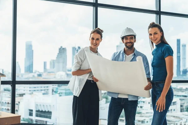 Group of smart architect engineer looking at camera while holding project plan. Skilled manager team discuss about building construction while standing near with city view. Team working. Tracery.