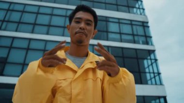 Asyalı dansçıyla dikilirken kameraya poz veren İspanyol sokak dansçısı. Çekici bir hippi, ellerini çatıdaki hip hop müziğine doğru hareket ettiriyor. Açık hava sporu 2024 hiphop..