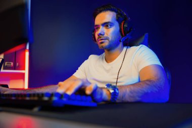 Akıllı oyun kurucusu, dijital neon ışıklandırma stüdyosundaki sosyal medya uygulamasında başkalarıyla iletişim kurmak için kulaklık ve mikrofon kullanan takım üyeleriyle konuşuyor. Tahmin et..