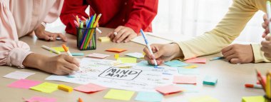 Yaratıcı iş adamları, zihin haritalama kullanarak pazarlama stratejisi ve iş planı hakkında beyin fırtınası yapıyorlar. Girişim ekibi kağıda yazmak için birlikte çalışır. Eline odaklan. - Yakın çekim. Değiştirilmiş.