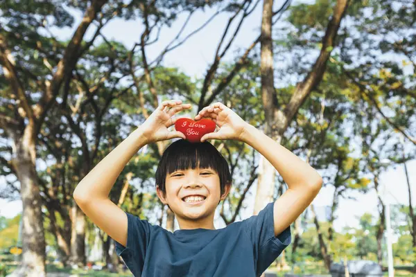 Eco awareness campaign promoting environmental protection with happy asian boy holding heart as symbol of love for nature and ecology for future greener sustainable Earth. Gyre
