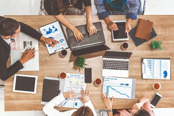Modern ofisteki iş adamları ve iş kadınlarıyla grup toplantısındaki iş adamlarının en üst düzey görüşü, masada dizüstü bilgisayar, kahve ve belge ile. Kurumsal şirketler uds