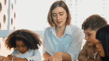 Masada masal kitabı ve renkli kitapla otururken çeşitli öğrencilere hikaye anlatan profesyonel beyaz bir öğretmen. Eğitmenden renkli resim alırken akıllı öğrenci dinlemeyi öğrenir. Etkinlik.