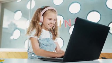 Dizüstü bilgisayarda çalışan ya da online sınıfta okuyan genç bir öğrenci. Ev ödevi yaparken ya da müzik dinlerken bilgisayarda yazan beyaz bir kız. Kulaklık takan küçük bir çocuk. Yaratıcı öğrenme. Etkinlik.