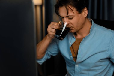 Satış müdürü bilgisayar üzerinde çalışıyor ve modern ev ofisinde gece kahve içerken iş grafiği raporuyla karşılaştırma yapıyor. Çeyrek yıllık sunum karlı ürün için. Bireysel.