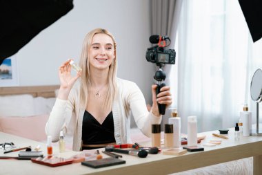 Sosyal medya için güzellik ve kozmetik video içeriği hazırlayan genç bir kadın. Güzellik blogcusu kameraya gülümserken seyirciye ya da takipçilere güzellik teninin nasıl uygulanacağını gösteriyor. Blithe
