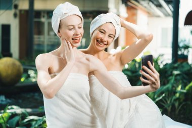 Beyaz havluyla güzel ciltli bir çift güzel kadın açık havada barışçıl doğal çevreyle çevrili bir şekilde fotoğraf çekiyorlar. Güzellik ve sağlıklı spa konsepti. Huzur.