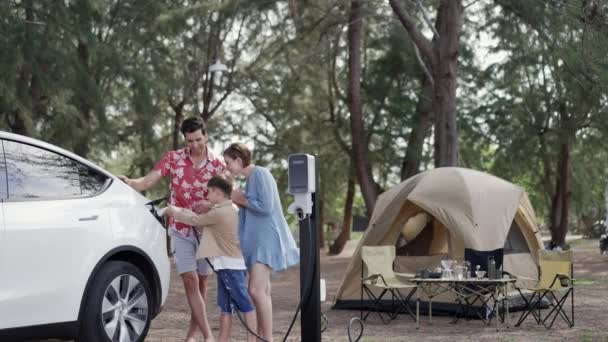 为了可持续的未来 野外探险和野外家庭度假露营都要乘坐环保汽车 可爱的家人在营地用电动车充电站给电动车充电 太奇怪了 — 图库视频影像