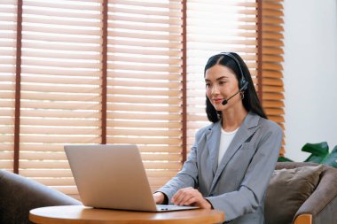 Kadın çağrı merkezi operatörü ya da müşteri hizmetleri çalışanı, müşteriye yardım etmek için kulaklıkla konuşurken çalışma alanı üzerinde çalışıyor. Profesyonel modern iş hizmeti. Blithe