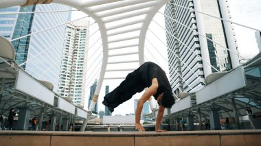 Genç Asyalı hippi şehir merkezinde insanların etrafında ayak izlerini gösteriyor. Şık bir sokak dansçısı B-boy ya da serbest dans eder. Açık hava sporu 2024. Break dans. Yumuşak bir şekilde..