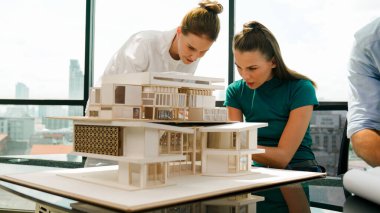 Akıllı mimar takımı ev tasarımı hakkında tartışırken yakışıklı erkek işçi dizüstü bilgisayar kullanarak fikir sunuyor. Profesyonel mühendis paylaşımı, beyin fırtınası tasarımı. İş tasarımı. İzleme