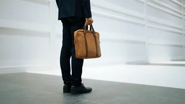 Closeup of professional business man leg walking while holding bag. Cropped image of project manager focus on leg. Traveling, moving, journey, walking, getting a new position, job changing. Exultant.