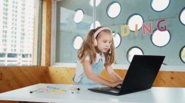 Dizüstü bilgisayarda çalışan ya da online sınıfta okuyan genç bir öğrenci. Beyaz kız ödevlerini yaparken ya da müzik dinlerken dizüstü bilgisayarda daktilo kullanıyor. Kulaklık takan küçük bir çocuk. Yaratıcı öğrenme. Etkinlik.