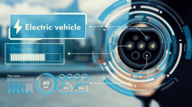 Kameranın önüne odaklanmış EV şarj cihazı bulanık şehir manzaralı akıllı dijital batarya durum hologramını gösterir. Alternatif temiz enerji kullanan EV araba şarjı CO2 salınımını azaltıyor. İnceleyin