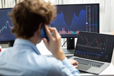 Başarılı genç yatırımcı, akıllı telefondan iş ortağına Dinamik Finansal Değişim Yatırım Dizüstü bilgisayarı ile modern ofisteki mevcut pazar grafiğinde gerçek zamanlı arıyor. Toplayıcı.