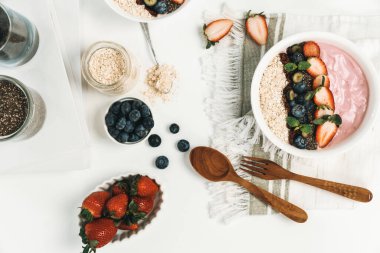 Meyvelerin sunduğu yoğurt malzemelerini çilek, yulaf, kuru üzüm ve nane şekeriyle süslenmiş Chia tohumu ile beyaza boyarız. Pembe arka plan. Sağlıklı süt ürünleri seti. Bireysel.
