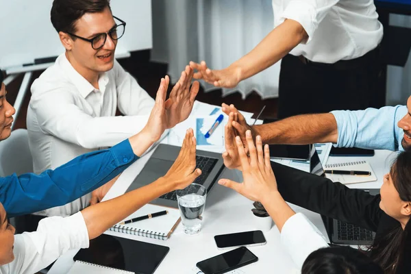 Diverse group of office employee worker high five after making agreement on strategic business marketing planning. Teamwork and positive attitude create productive and supportive workplace. Prudent