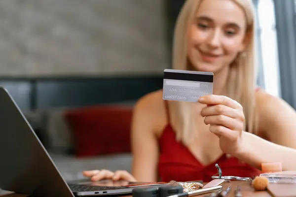Young woman using laptop with credit card for internet banking, online shopping E commerce by online payment gateway at home office. Modern and convenience online purchasing with debit card. Blithe