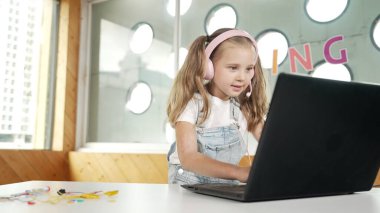 Dizüstü bilgisayarda çalışan ya da online sınıfta okuyan genç bir öğrenci. Ev ödevi yaparken ya da müzik dinlerken bilgisayarda yazan beyaz bir kız. Kulaklık takan küçük bir çocuk. Yaratıcı öğrenme. Etkinlik.