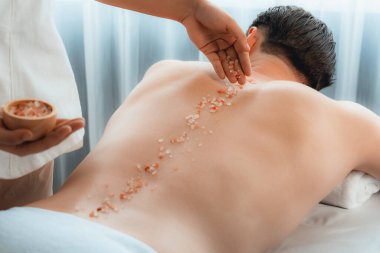 Lüks spa salonunda sıcak mum ışığı atmosferi olan lüks kaplıcalarda deri dökme tedavisi gören mutlu bir adam. Sağlık kaplıcasında güzellik tedavisiyle tuz temizliği. Sessiz.