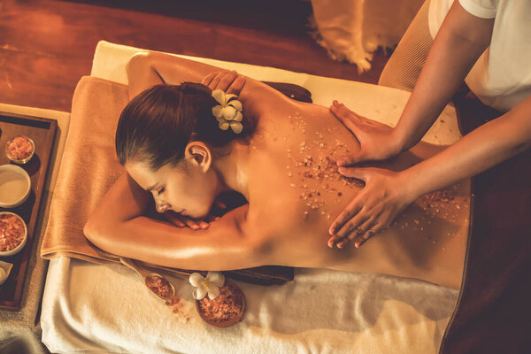 Женщина-клиент, проводящая пилинг в роскошном спа-салоне с теплым свечой окружающей среды. Косметическое лечение бальзамическим скрабом в Health spa scrub. Quiescent