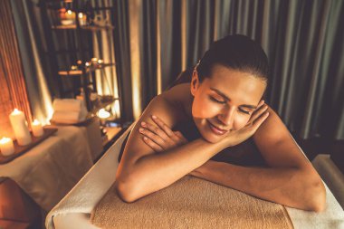 Beyaz kadın müşteri stres önleyici spa masajının keyfini çıkarıyor ve lüks otel ya da otelde sıcak mum ışığında güzellik teniyle eğleniyor. Sessiz.