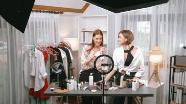 İki kadın nüfuzlu partner sosyal medya veya blog için canlı yayın yapan video klip inceleme derisi çekiyorlar. Kozmetik stüdyosu ışıklandırması olan genç bir kız pazarlama oturumu çevrimiçi yayın yapıyor.