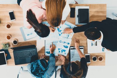 Modern ofisteki iş adamları ve iş kadınlarıyla grup toplantısındaki iş adamlarının en üst düzey görüşü, masada dizüstü bilgisayar, kahve ve belge ile. Kurumsal şirketler uds